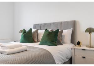 ein Schlafzimmer mit einem großen Bett mit grünen Kissen in der Unterkunft Cosmopolitan Living: Upscale 1BR Gem in Beckenham in Beckenham