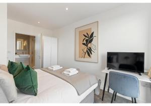 Schlafzimmer mit einem Bett und einem Schreibtisch mit einem TV in der Unterkunft Cosmopolitan Living: Upscale 1BR Gem in Beckenham in Beckenham