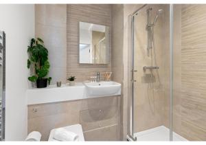 ein Bad mit einem Waschbecken und einer Duschkabine in der Unterkunft Cosmopolitan Living: Upscale 1BR Gem in Beckenham in Beckenham