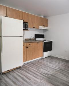 an empty kitchen with white appliances and wooden cabinets at Studio apartment with 1 bed - 242 in Montréal