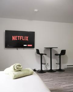 uma televisão numa parede com quatro cadeiras e bancos em Studio apartment with 1 bed - 242 em Montreal