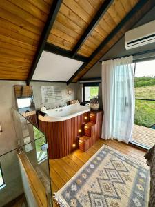 a large bathroom with a tub and a large window at Cabanas Sonho Rosa - com banheira hidro e cesta de café cortesia na primeira manhã in Imbituba