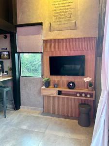 a living room with a tv on a wall at Cabanas Sonho Rosa - com banheira hidro e cesta de café cortesia na primeira manhã in Imbituba