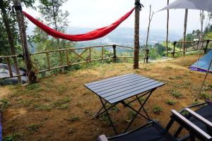 a picnic table and a hammock on top of a hill at ZOYA HILLS in Pondok Cipaseban