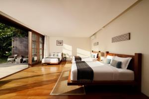 a bedroom with two beds and a patio at Villa Amita by Nakula in Kerobokan