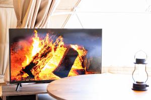 - une télévision assise sur une table à côté d'un feu dans l'établissement THE GLAMPING PLAZA 伊勢志摩BASE, à Ugata