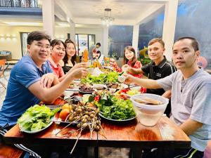 un grupo de personas sentadas en una mesa comiendo comida en Sapphire Villa - Venuestay en Luong Son