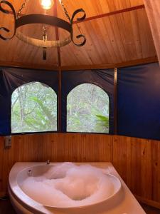 a bath tub in a room with two windows at Villas del Rio Glamping in San Francisco