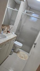 uma casa de banho com um WC, um lavatório e um espelho. em Apt Confort - Suíte c/ hidro - 9 min da praia a pé em Itapema