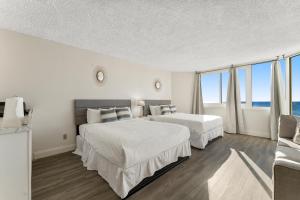 a bedroom with two beds and a large window at Top of the Gulf 523 - Beach Front Resort With Ocean View in Panama City Beach