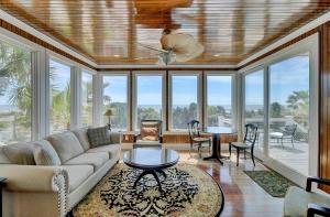 a living room with a couch and tables and windows at 910 Ocean Boulevard in Isle of Palms