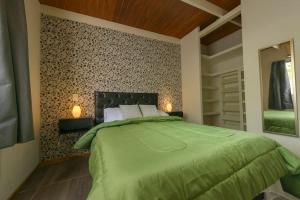 een slaapkamer met een groot groen bed met 2 lampen bij Departamento moderno 6ta sección in La Cieneguita