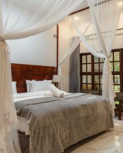 um quarto com uma cama grande e cortinas brancas em Jacaranda Lodge em Victoria Falls
