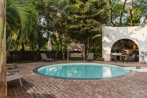 una piscina en un patio con mesa y sillas en Jacaranda Lodge, en Victoria Falls