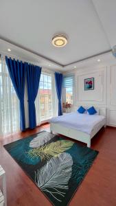 a bedroom with a large bed with blue curtains at Da Lat Mom House in Ấp Kim Thạch