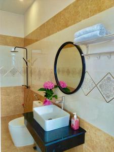 a bathroom with a sink and a mirror and a toilet at Da Lat Mom House in Ấp Kim Thạch