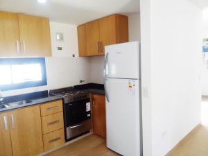 a white refrigerator in a kitchen with wooden cabinets at House, Summer in Villa Gesell