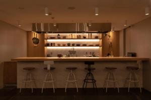 東京的住宿－CAFE/MINIMAL HOTEL OUR OUR，厨房设有酒吧,四周摆放着凳子