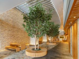 two trees in a hallway with benches and a brick wall at The OneFive Sendai in Sendai