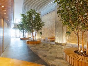 un pasillo con árboles y bancos en un edificio en The OneFive Sendai en Sendai