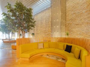 um sofá amarelo num quarto com uma parede de tijolos em The OneFive Sendai em Sendai