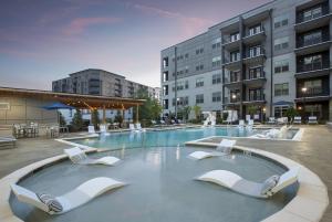 a large swimming pool with white chairs and buildings at Luxury 2br Apartment (Buckhead) in Atlanta