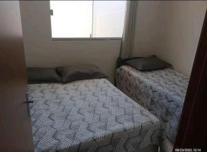 two beds in a small room with a window at Casa a 5 km de Luziânia 1 quarto com ar-condicionado in Cidade Ocidental
