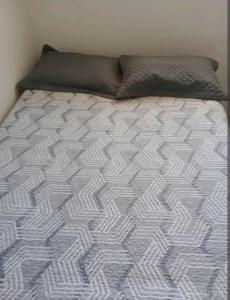 an unmade bed with a gray and white comforter at Casa a 5 km de Luziânia in Cidade Ocidental