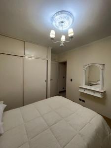 Un dormitorio con una gran cama blanca y una lámpara de araña. en La casa de Cate en Mar de Ajó