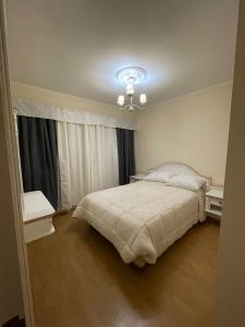 1 dormitorio con cama y lámpara de araña en La casa de Cate en Mar de Ajó