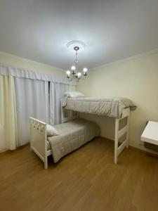 1 dormitorio con 2 literas y lámpara de araña en La casa de Cate en Mar de Ajó