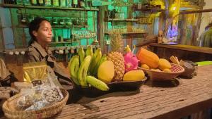 象島的住宿－Seree Bungalows，坐在桌子上的女人,上面有水果