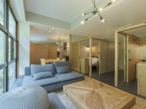 a living room with a blue couch and a bedroom at Hishino Onsen Tokiwakan in Komoro