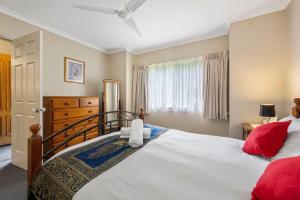 a bedroom with a large white bed with red pillows at Happy Paws Bright Hideaway in Bright