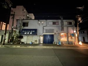 un edificio con una puerta azul en una calle por la noche en マルチステイ大阪天保山22 en Osaka