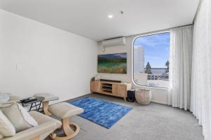 a living room with a couch and a large window at Oceanside Sunset Views in Mount Maunganui