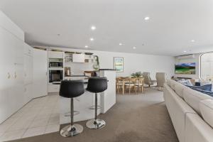 a kitchen and living room with a couch and chairs at Oceanside Sunset Views in Mount Maunganui