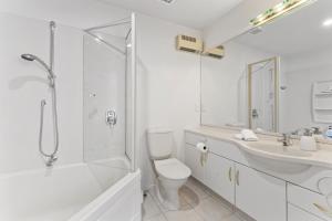 a bathroom with a toilet and a shower and a sink at Oceanside Sunset Views in Mount Maunganui