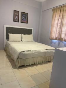 a bedroom with a large bed with two pictures on the wall at ROYAL LILY TANAH RATA BY JUNIKASTAY in Tanah Rata