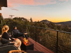 a man and woman sitting on a deck watching the sunset at Award-winning A-frame Chalet W Cedar Tub & Views in Julian