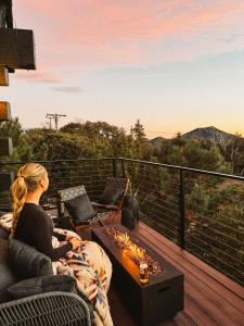 a woman sitting on a couch on a deck watching the sunset at Cedar Hot Tubsunset Viewsluxurious in Julian