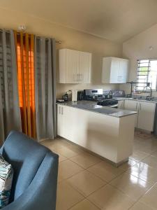 a kitchen with white cabinets and a blue chair in it at Finest Accommodation Lot 1577 Phoenix Park Phase 4 Portmore St Catherine 