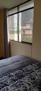 um quarto com uma cama e uma grande janela em Casa de George em Urubamba
