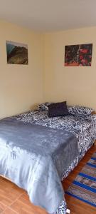 uma cama num quarto com um cobertor azul em Casa de George em Urubamba