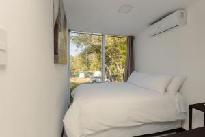 1 dormitorio con cama blanca y ventana en Mangoya Lounge 