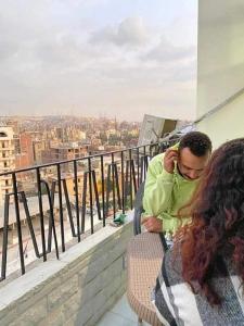a man and woman sitting on a balcony looking at a city at NADA Hostel in Cairo