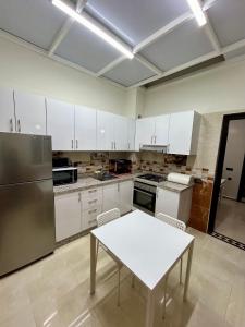 une cuisine avec des placards blancs et une table blanche dans l'établissement Appartement de luxe Marrakech Menara, à Marrakech