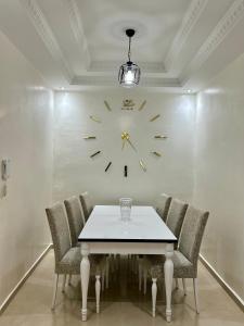 a dining room with a table and a clock on the wall at Appartement de luxe Marrakech Menara in Marrakesh