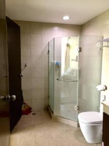 y baño con ducha de cristal y aseo. en The Pagdett Place - Unit 1502, en Cebú