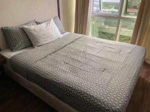 1 cama con edredón y almohadas grises y ventana en The Pagdett Place - Unit 1502, en Cebú